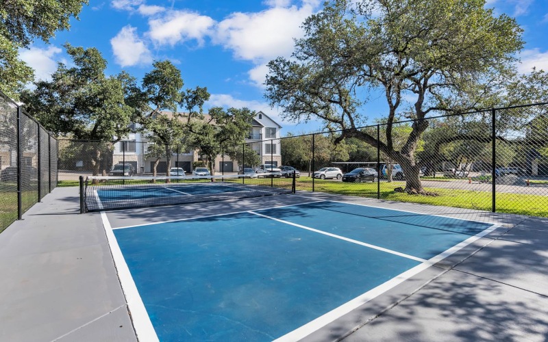 a tennis court with a fence and trees
